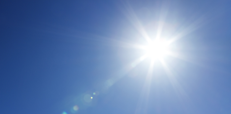 An image of the bright sun beaming down from a blue sky