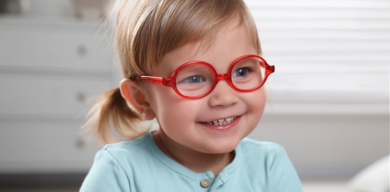 A cute little girl wearing a pair of red eyeglasses