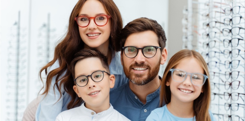 Smiling parents and their children in their new glasses at the eye doctor’s