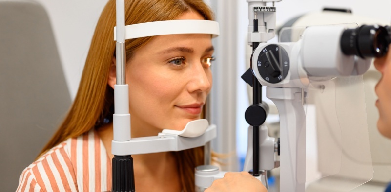 Eye doctor performing a detailed eye exam with a slit lamp on a young female patient during a consultation