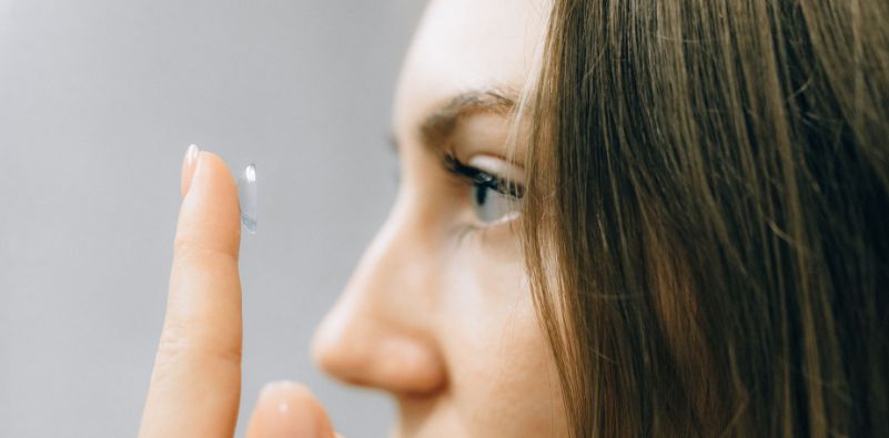 A woman preparing to insert a contact lens on her eye