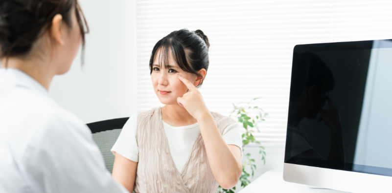 Patient pointing to eye during a consultation with an eye care professional