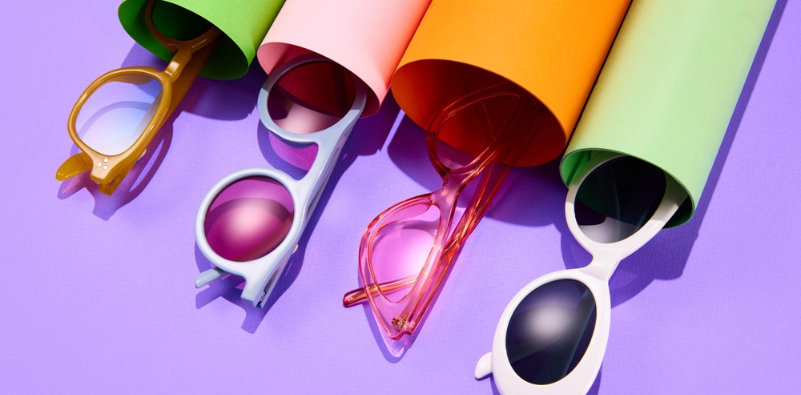 Colourful glasses in different shapes emerging from vibrant tubes against a purple background