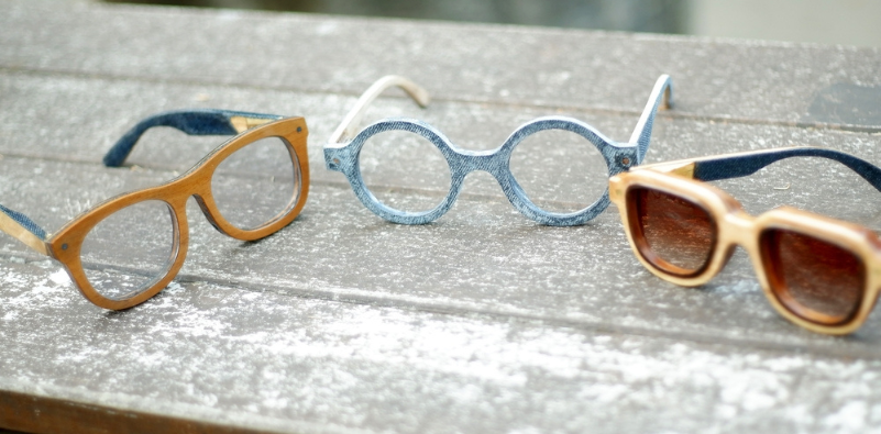 Three pairs of wooden-frame glasses displayed on a wooden bench