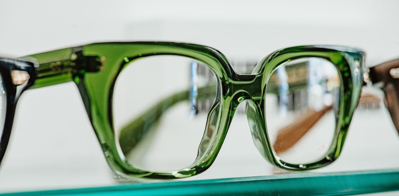 Translucent green glasses displayed on a glass shelf